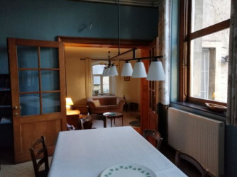Het aangename salon met zijn diepe ramen en houten vloer ligt centraal tussen keuken en eetkamer.